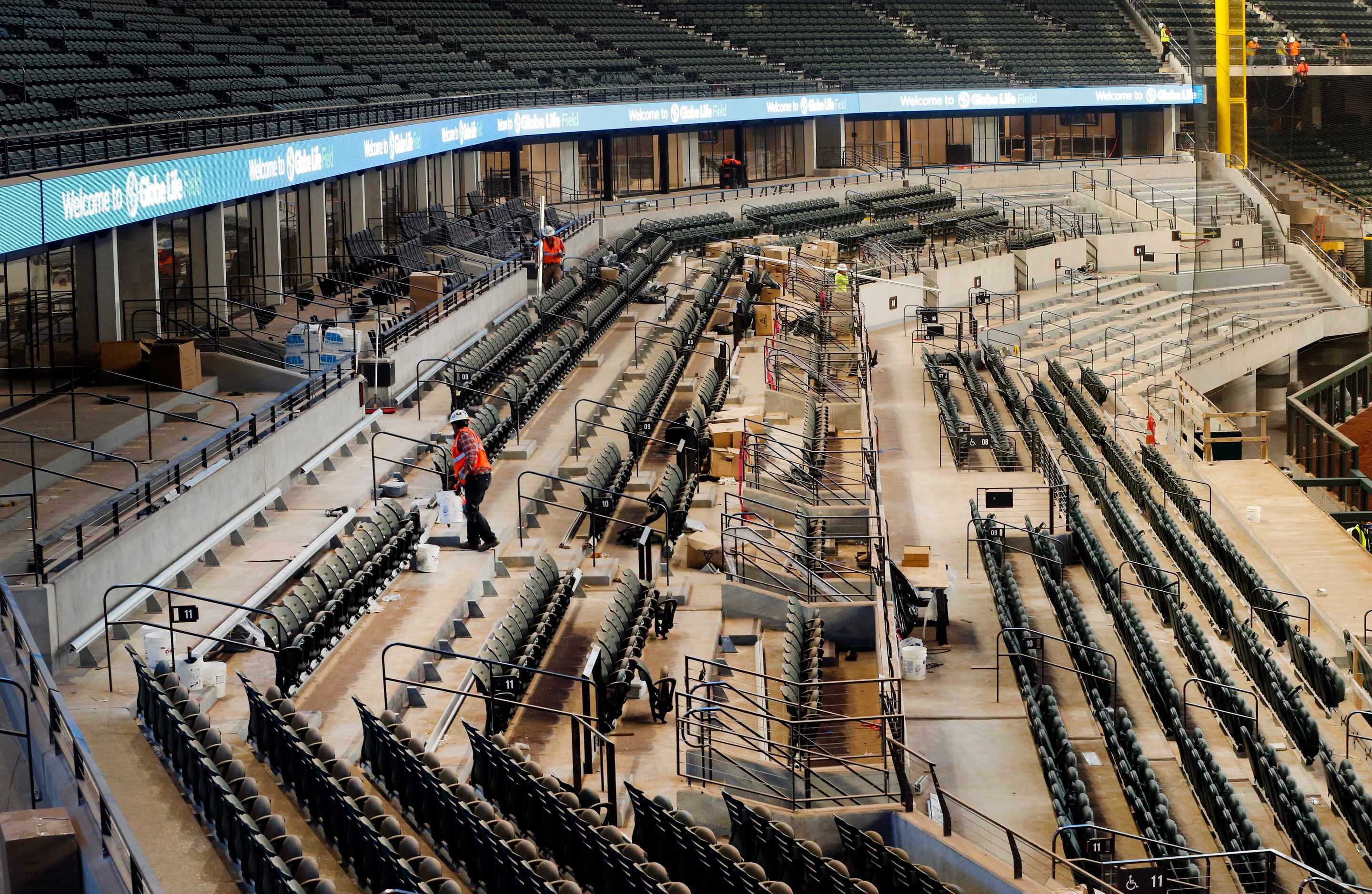 Workers install seats in the lower bowl of the new Globe Life Field under construction in...