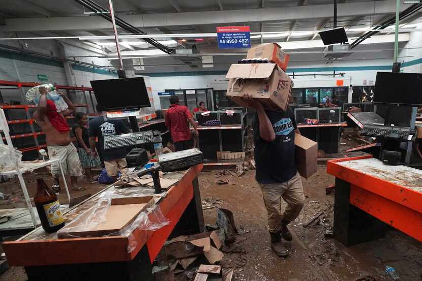 La gente saca cosas de un supermercado local luego de que el huracán Otis destrozara el...