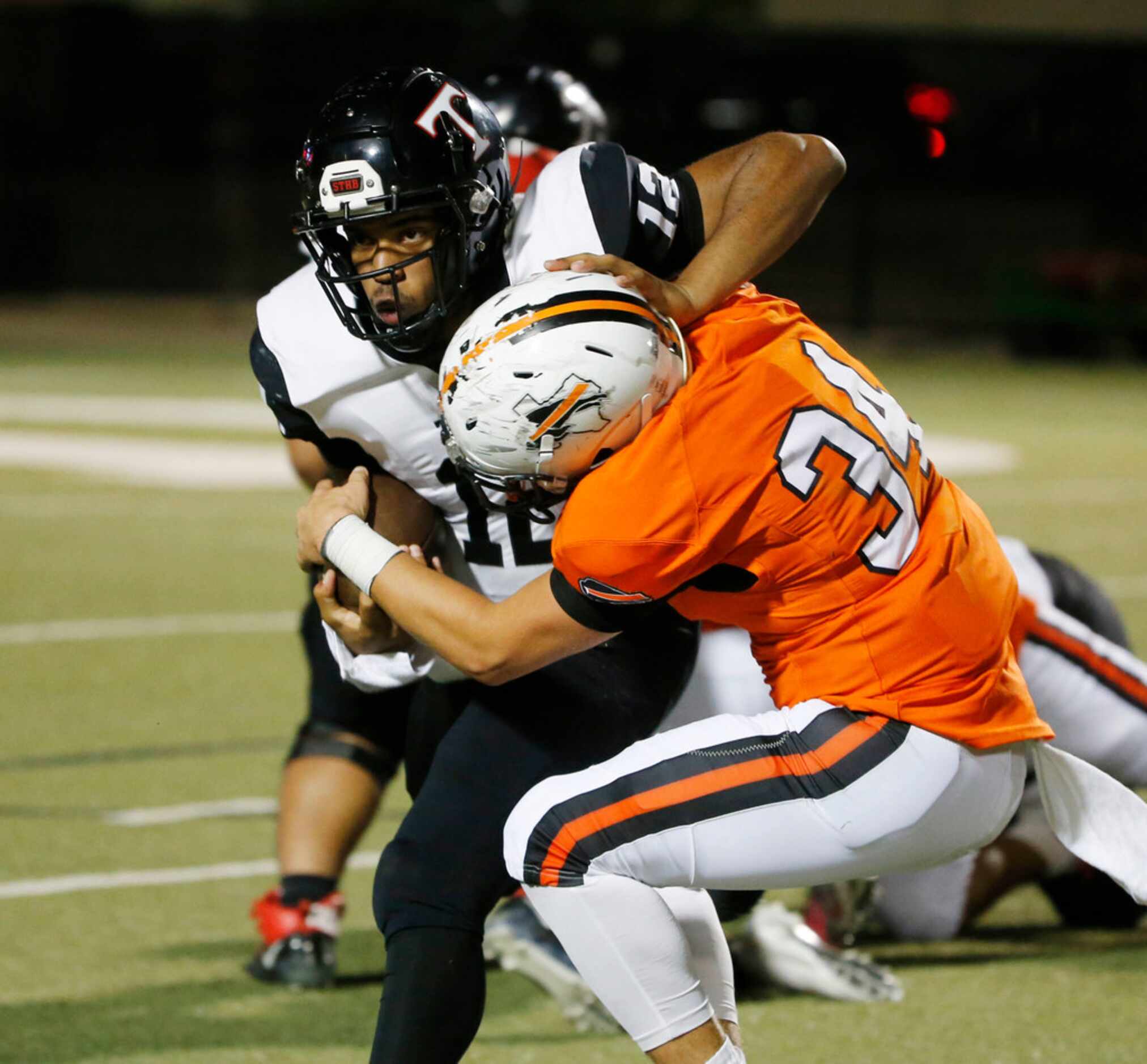 Euless Trinity quarterback Marcus Ervin (12) is tackled for a loss by Haltom's Brandon...