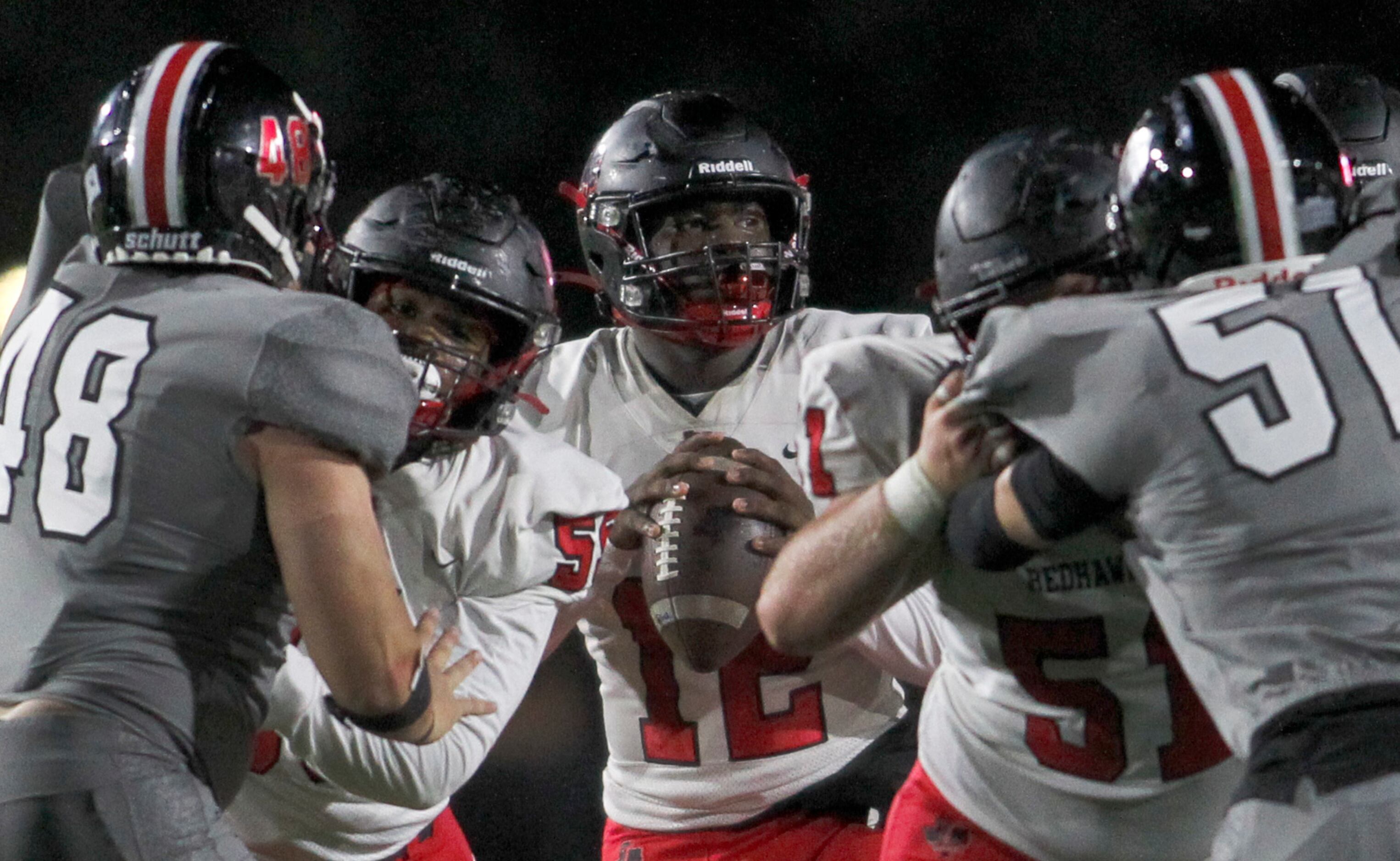 Frisco Liberty quarterback Keldric Luster (12), center, looks for a receiver behind the pass...