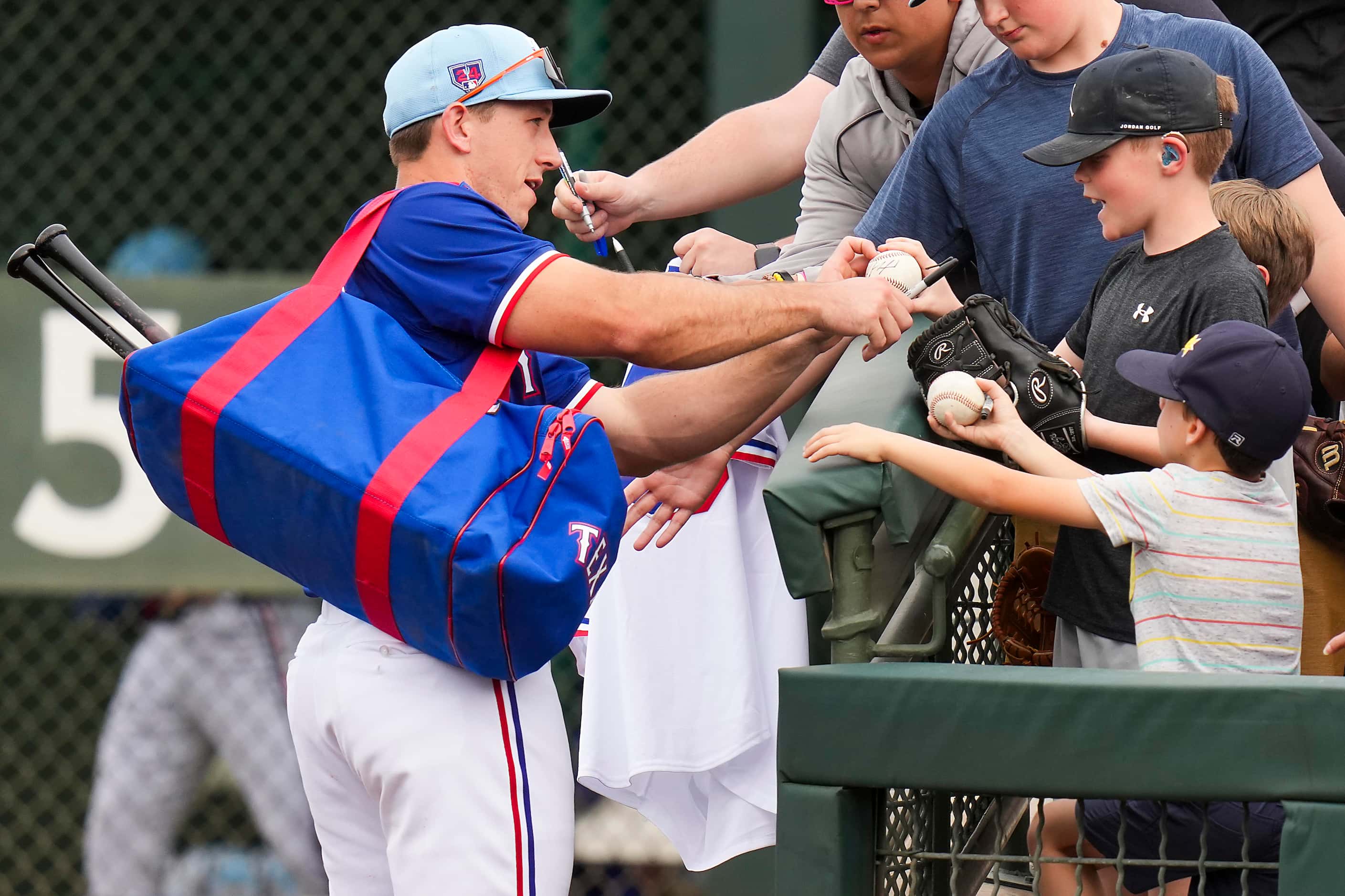 Texas Rangers outfielder Wyatt Langford signs autographs as he heads to the clubhouse during...