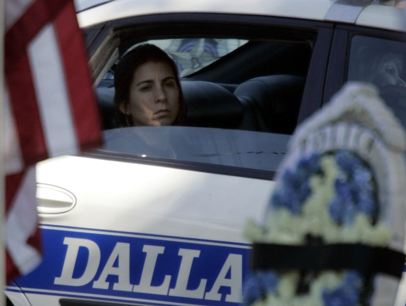 JoAnn DeMello Jackson sits in a Dallas Police squad car as she waits for the casket for her...