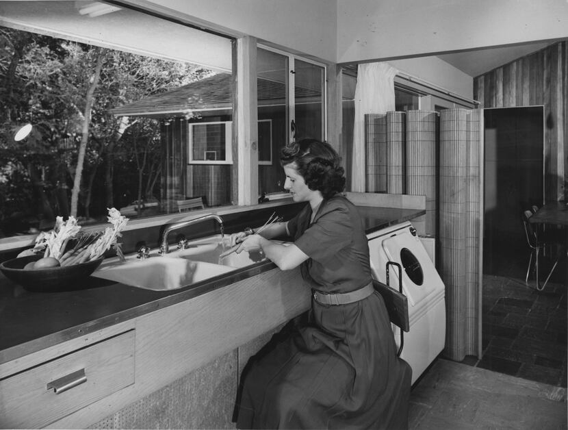 Jeanette Prinz cooks in the family kitchen in this 1950s photograph (the clothes washer is...