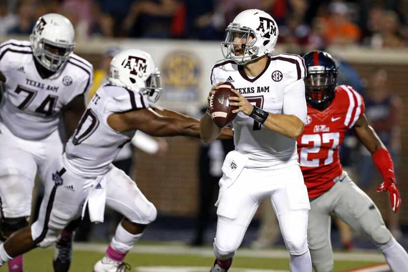 Texas A&M quarterback Jake Hubenak (7) looks for an open receiver while his teammates try to...