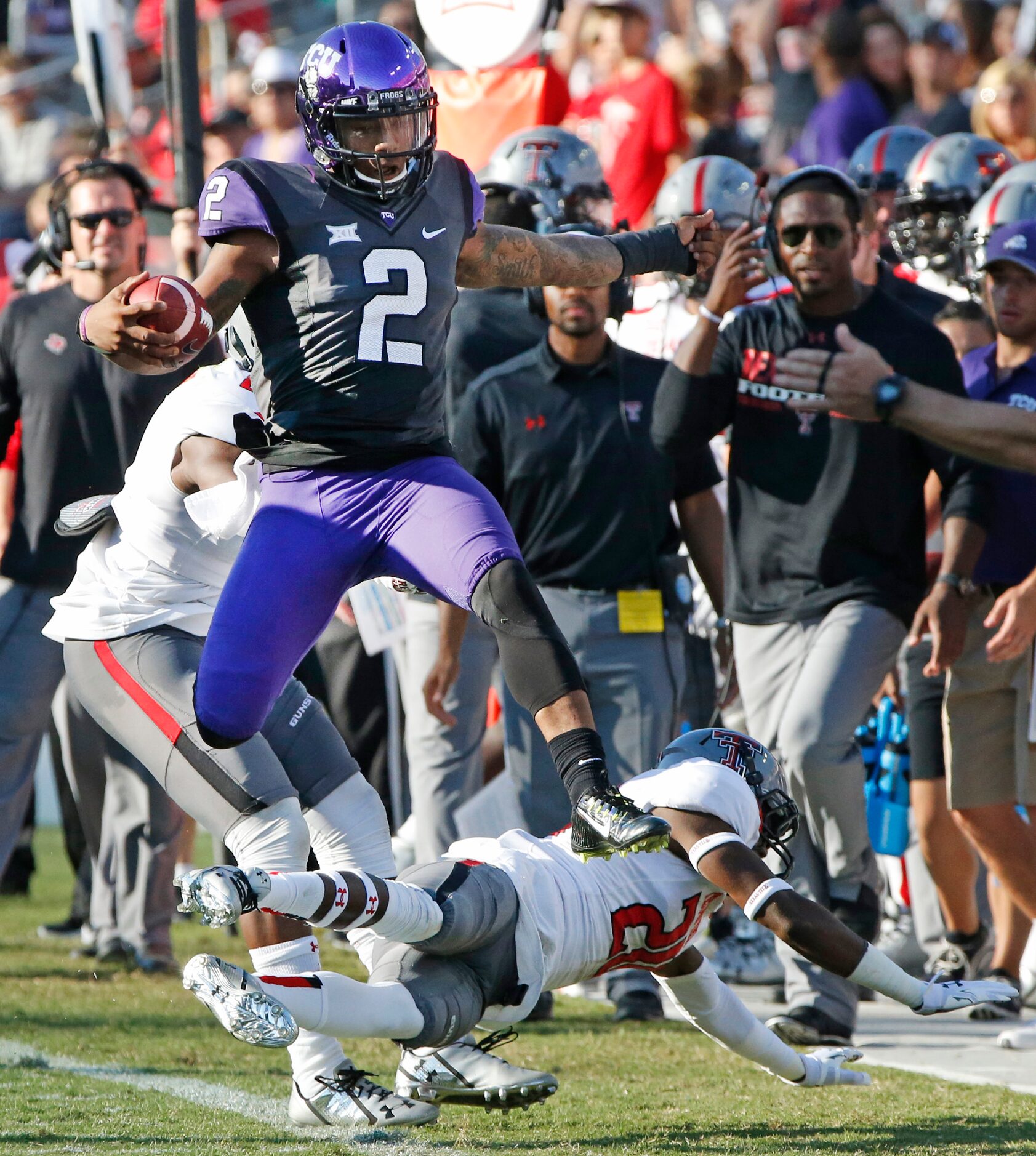 TCU quarterback Trevone Boykin (2) hurdles Texas Tech defensive back Tevin Madison (20) on a...