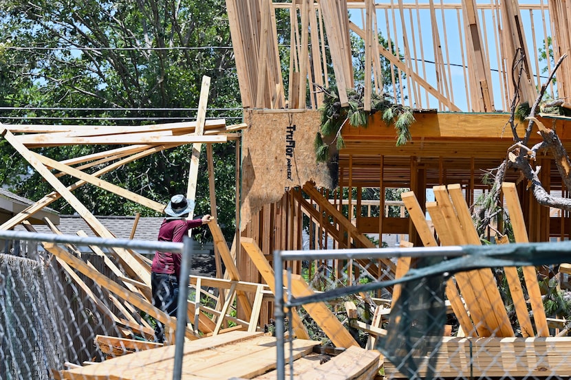 A worker cleans up damage to a residential house under construction in Houston, Wednesday,...