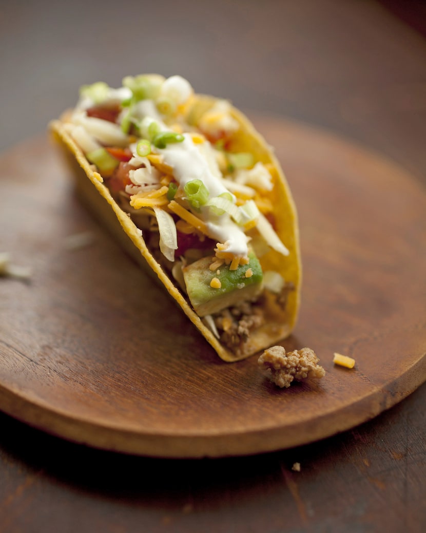 Un taco crujiente con carne molida, aguacate picado y queso rallado. AP