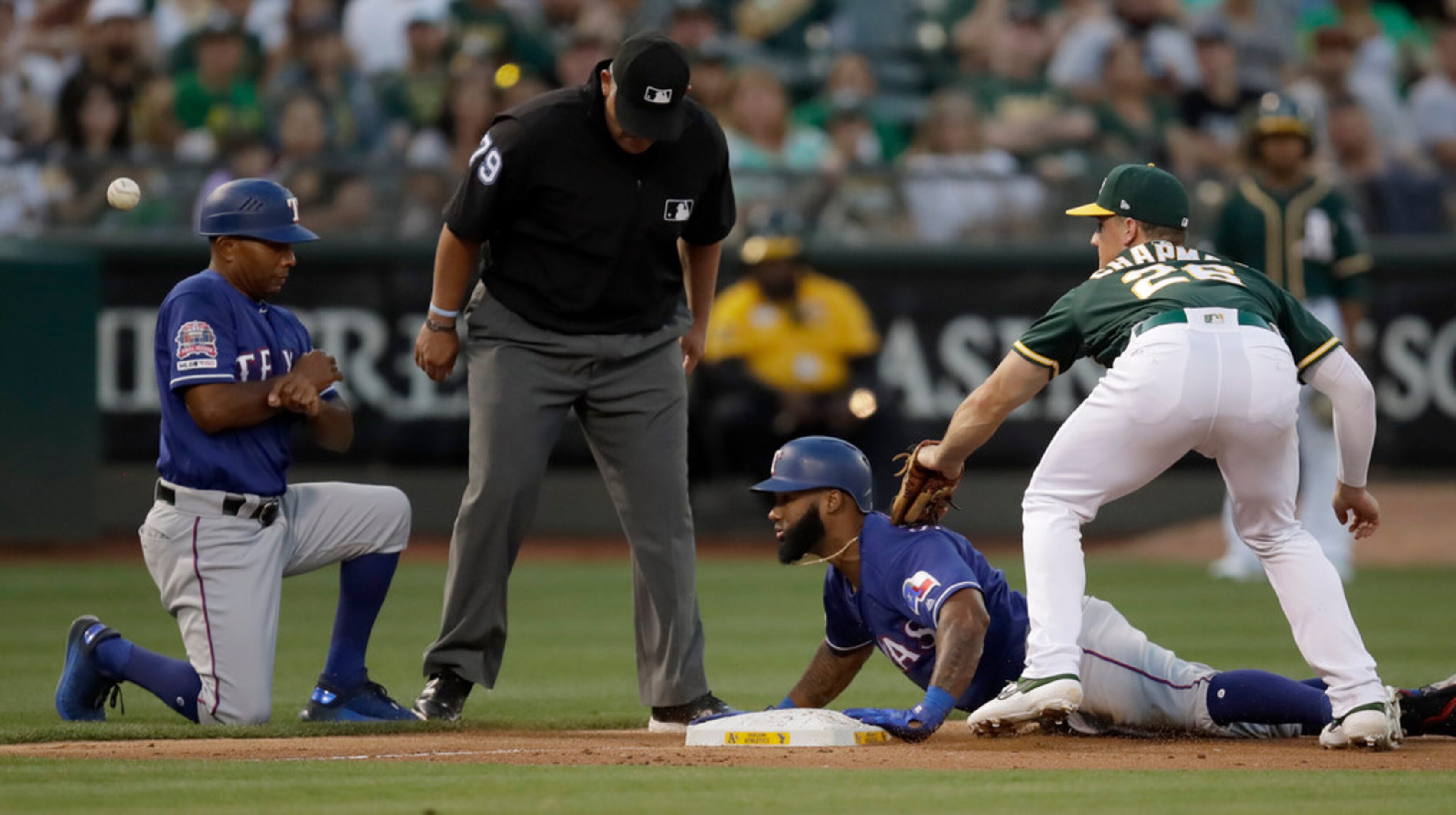 Texas Rangers' Danny Santana, second from right, slides past Oakland Athletics third baseman...