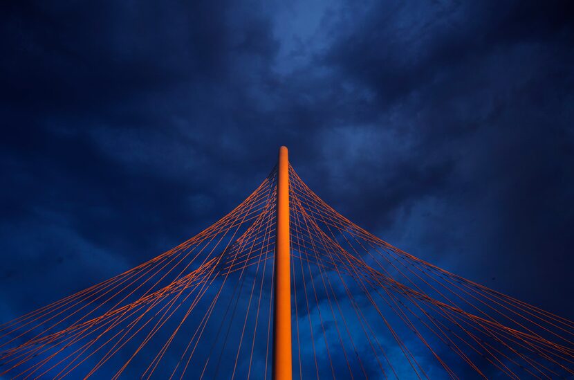 The setting sun illuminates the Margaret Hunt Hill Bridge and downtown Dallas after...