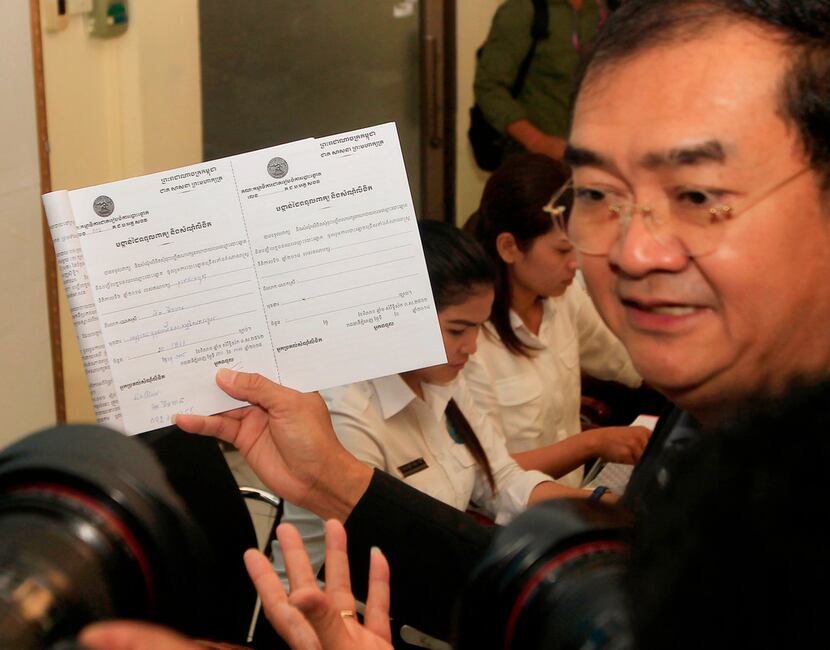 National Election Committee's Dim Sovannarom shows off a registration receipt of the...
