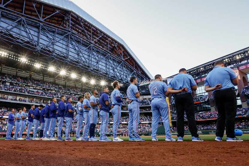 The Texas Rangers stand for the national anthem before a game against the Houston Astros at...