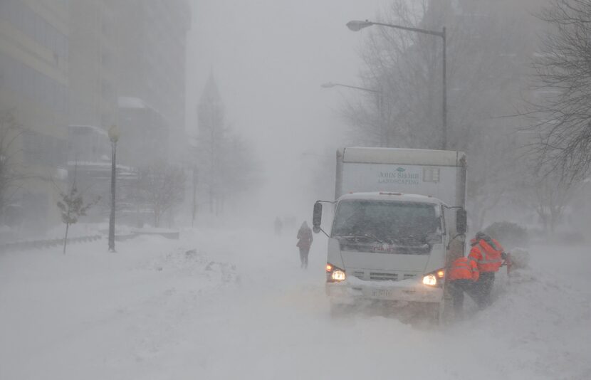  As the snow blows, a crew works to free a truck stuck in it, Saturday, Jan. 23, 2016 in...