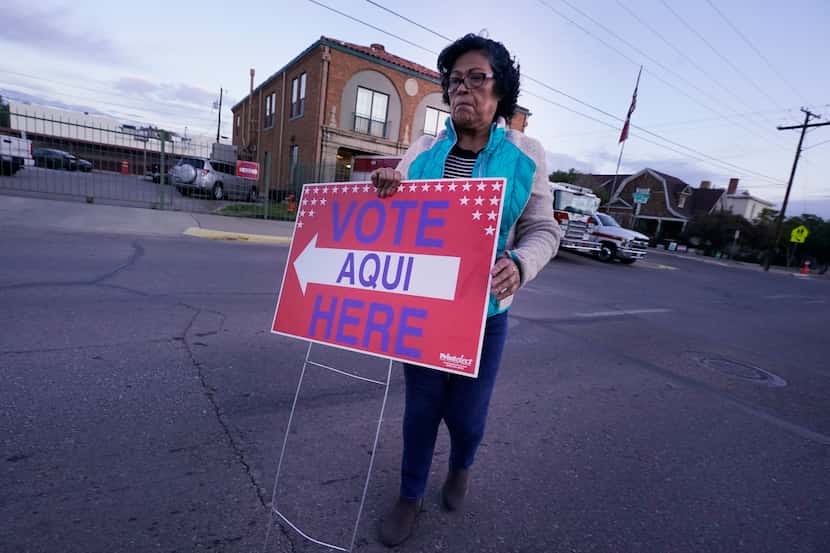 Election worker Ramona Ortiz walks across the street to places a sign outside a polling...