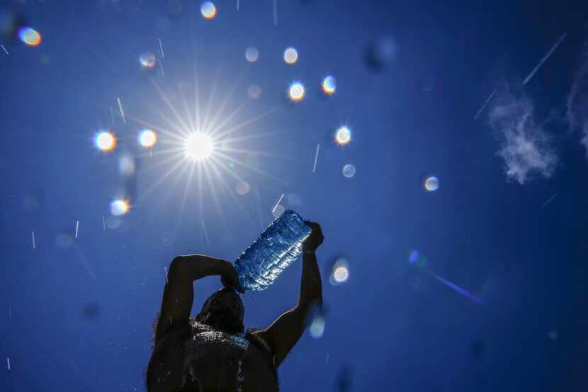 Un hombre se echa agua encima para refrescarse en un día caluroso en el Mediterráneo, en...