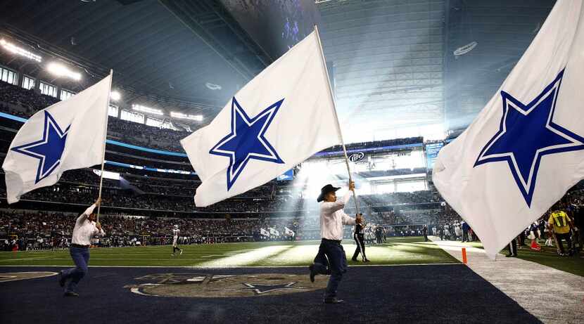 Dallas Cowboys spirit squad cary race across the field with flags after scoring on the...