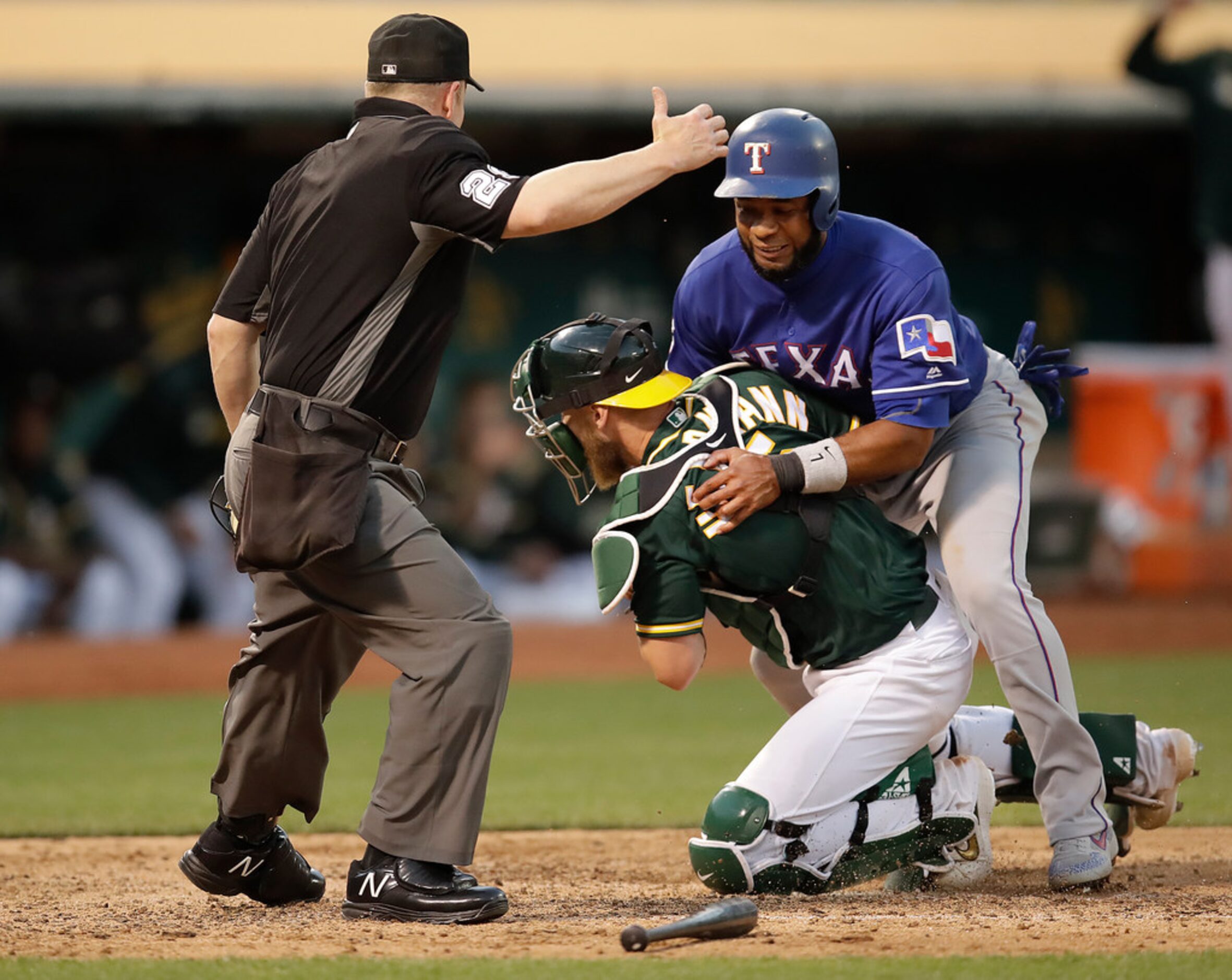 Texas Rangers' Elvis Andrus, top, collides with Oakland Athletics catcher Chris Herrmann in...