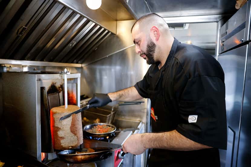 AJ Hedary shaves spit-roasted beef and lamb for a gyro inside his food truck in Fort Worth....