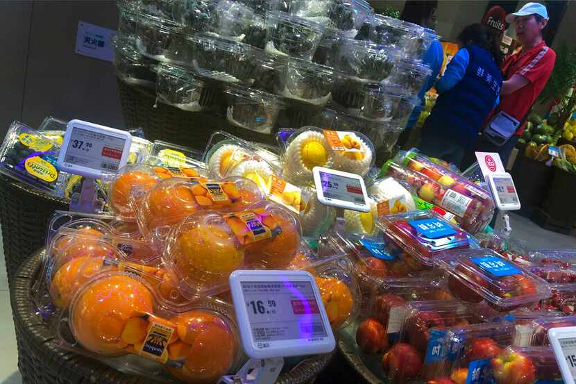 Un hombe charla con trabajadores cerca de una sección con fruta donde se ven naranjas de...