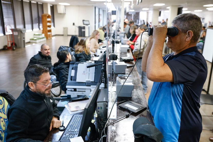 Consulate of Mexico employee Antonio Arredondo (left) attends Miguel Alvarado as he gets his...