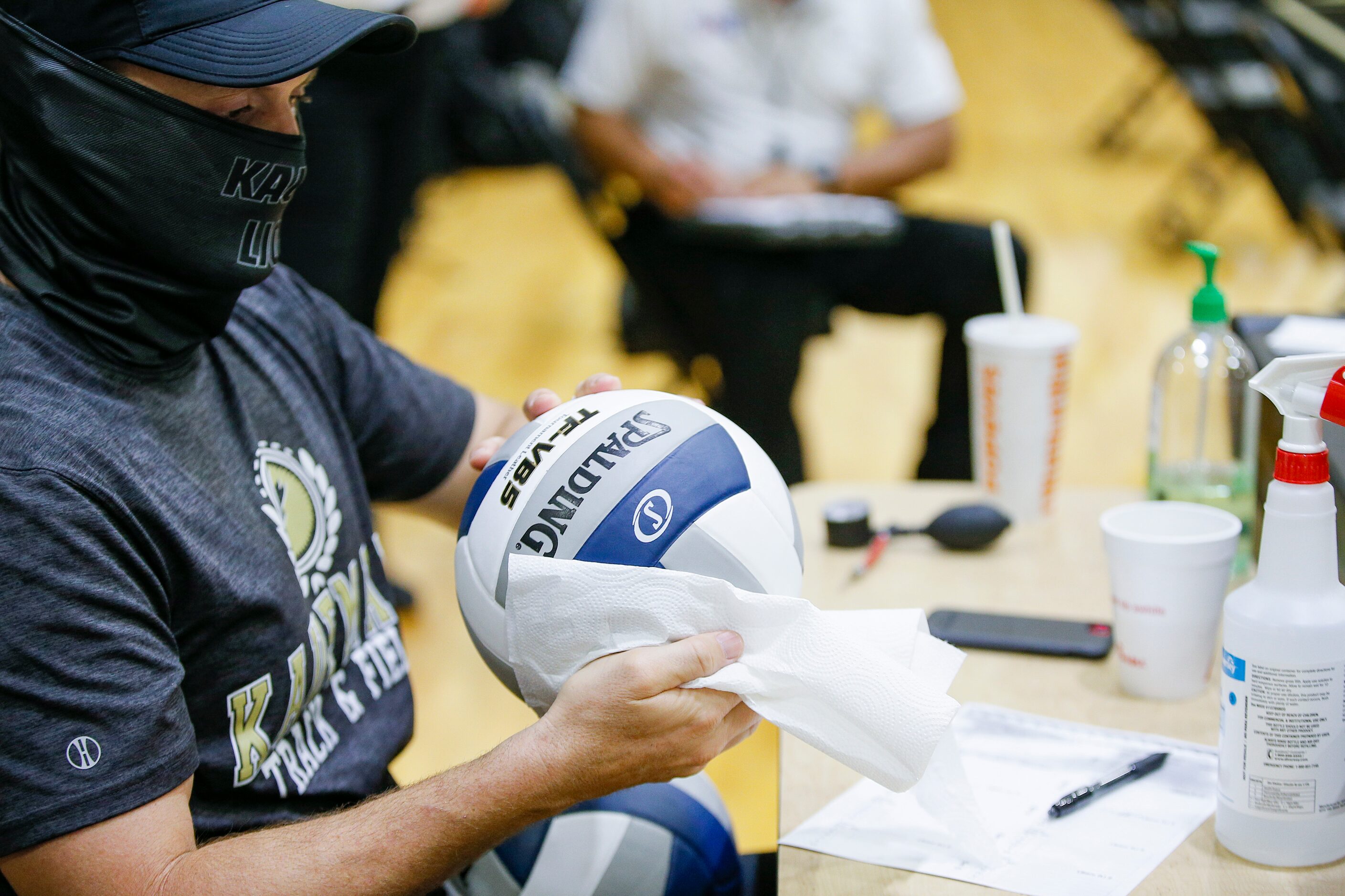 Kaufman High School girls cross country and track coach Denver Stone disinfects one of two...