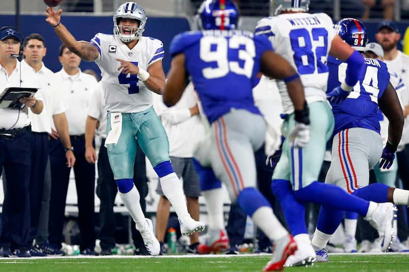 Before running out of bounds, Dallas Cowboys quarterback Dak Prescott (4) tosses a pass to...