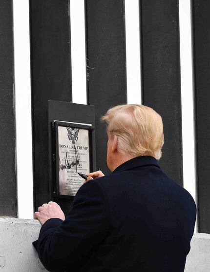 US President Donald Trump autographs a plaque on a section of the border wall in Alamo,...