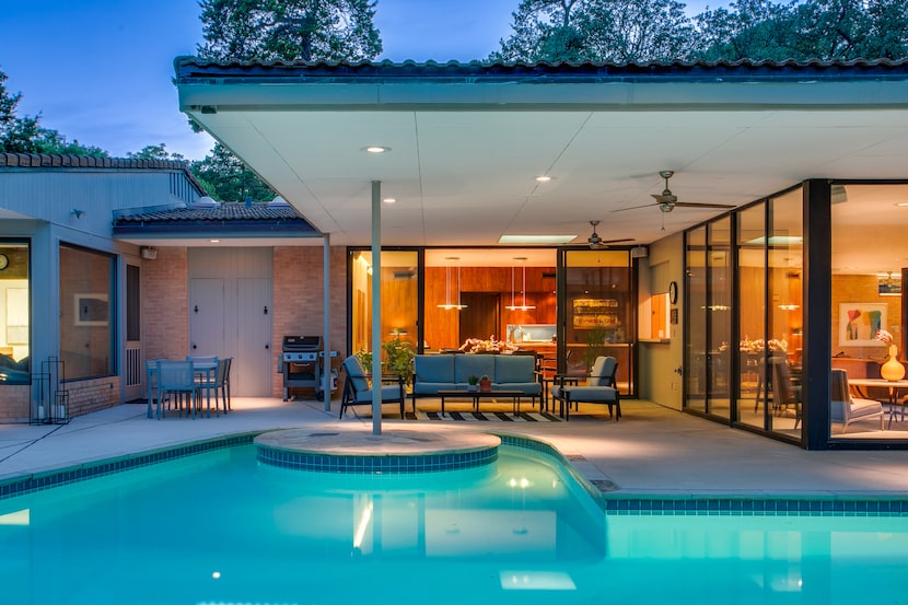 Pool at back of midcentury modern house lit up at night