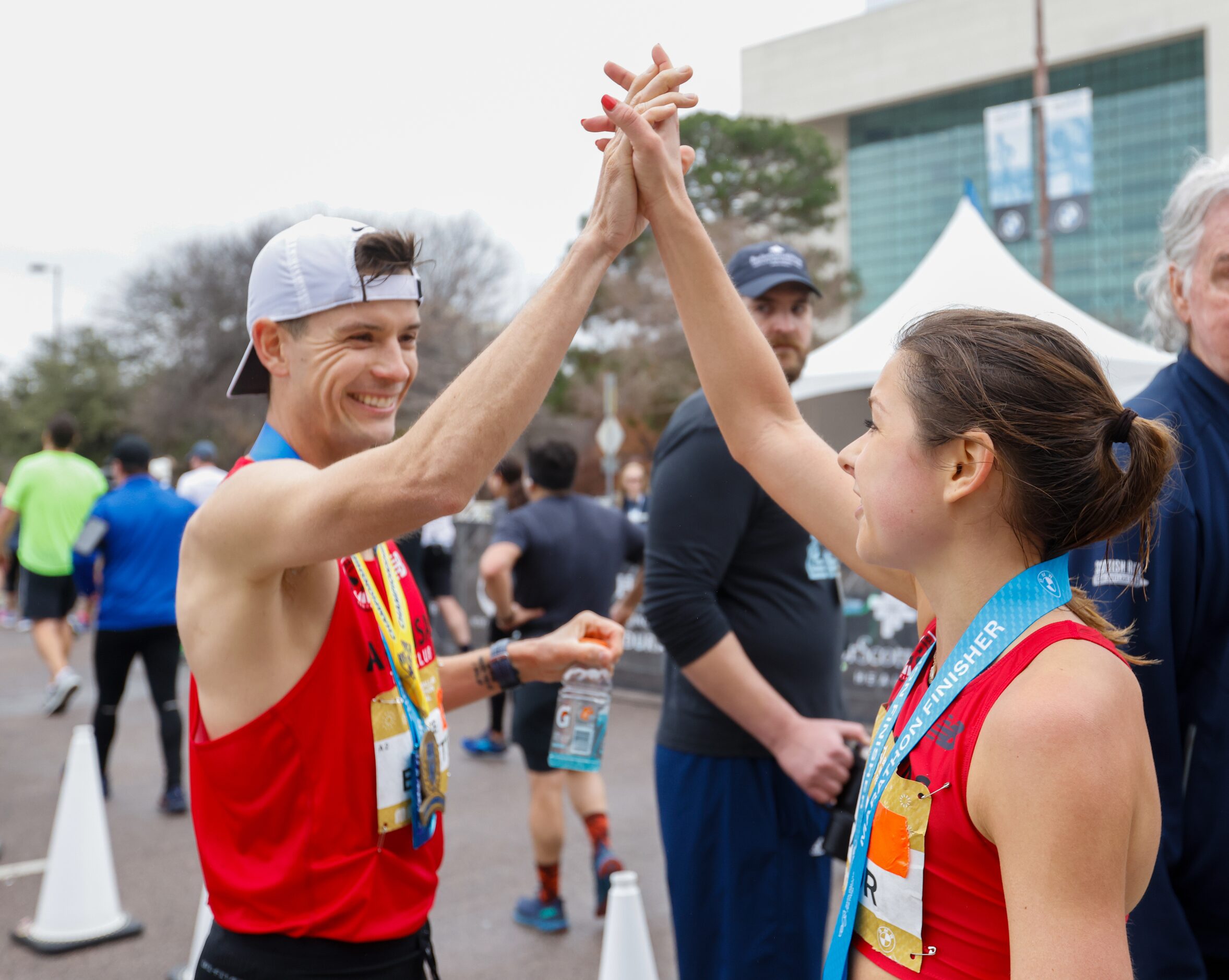 BMW Dallas Marathon winners Cameron Beckett (left) and Megan Taylor high-five just past the...