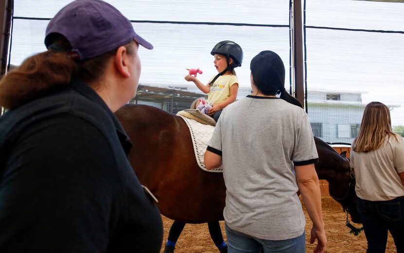 Occupational Therapist Joanna Rubenfield gives instructions to 3-year-old Mora Wolf while...