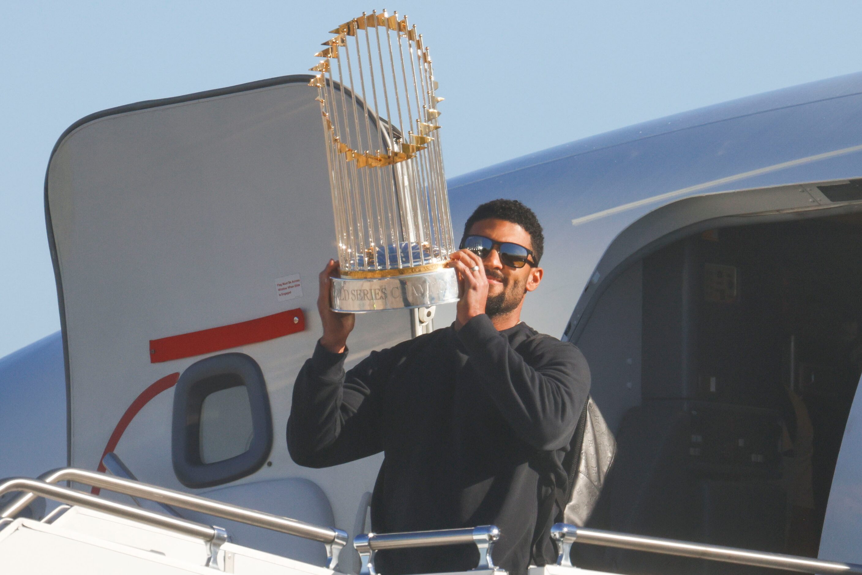 Texas Rangers’ Marcus Semien hoists the Commissioner's Trophy upon the arrival of the team...