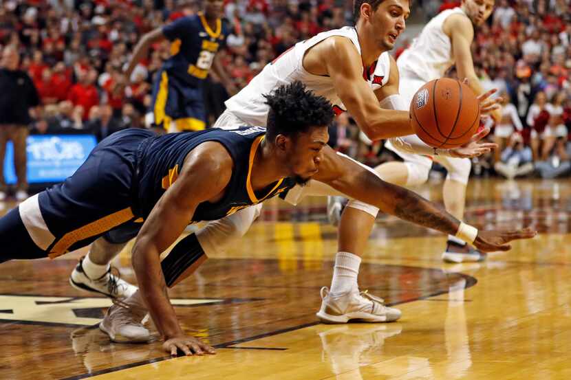 West Virginia's Derek Culver, left, and Texas Tech's Davide Moretti, right, dive for a loose...