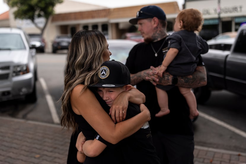 Mikayla Brown (left) comforts her son, Jax, near a park bench dedicated to Elijah in Paso...