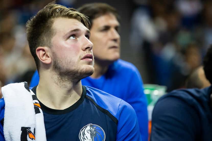 Dallas Mavericks guard Luka Doncic watches from the bench with owner Mark Cuban sitting over...