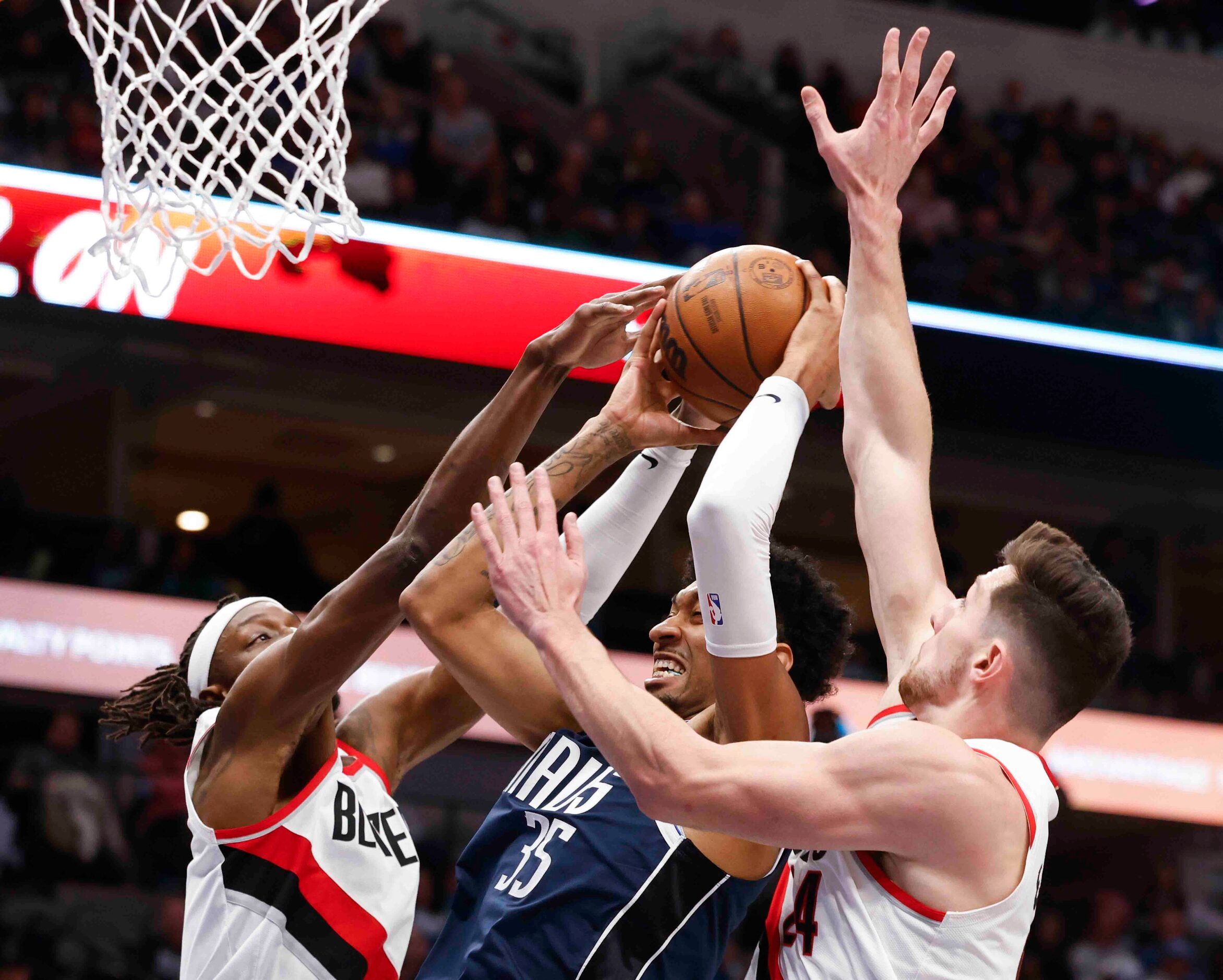 Dallas Mavericks forward Christian Wood (35), center, is fouled by Portland Trail Blazers...