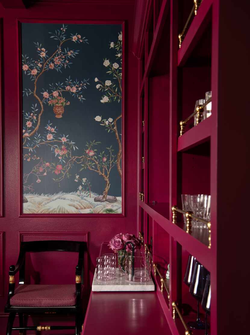 Room covered in burgundy paint on the cabinets and walls, with a burgundy chair and...