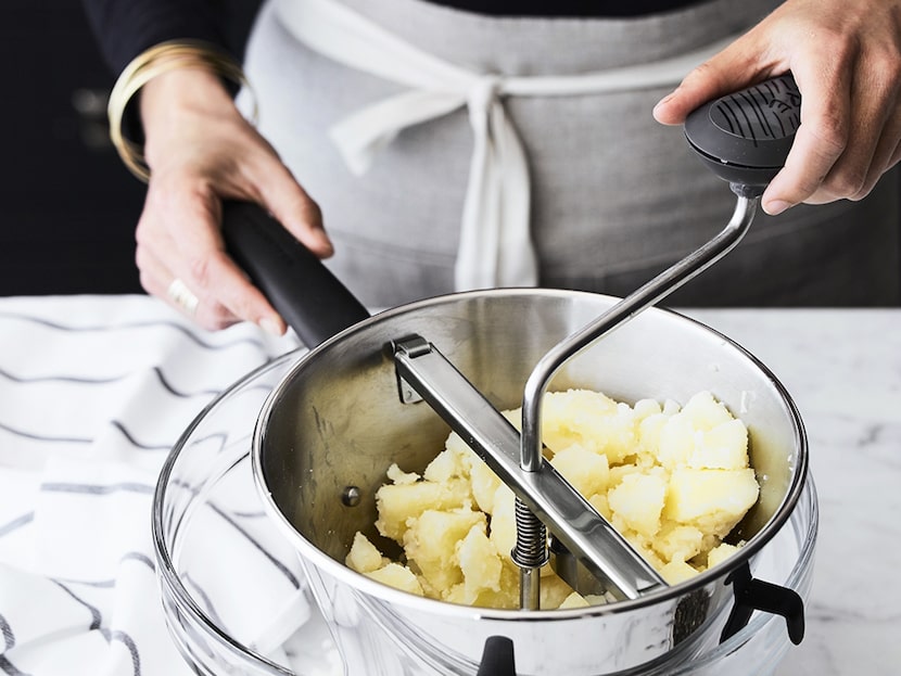 Person using a food mill to make mashed potatoes