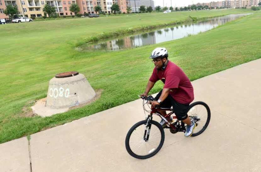 Andre Herron, who lives in the Las Colinas Urban Center, rides his bike along the trails in...