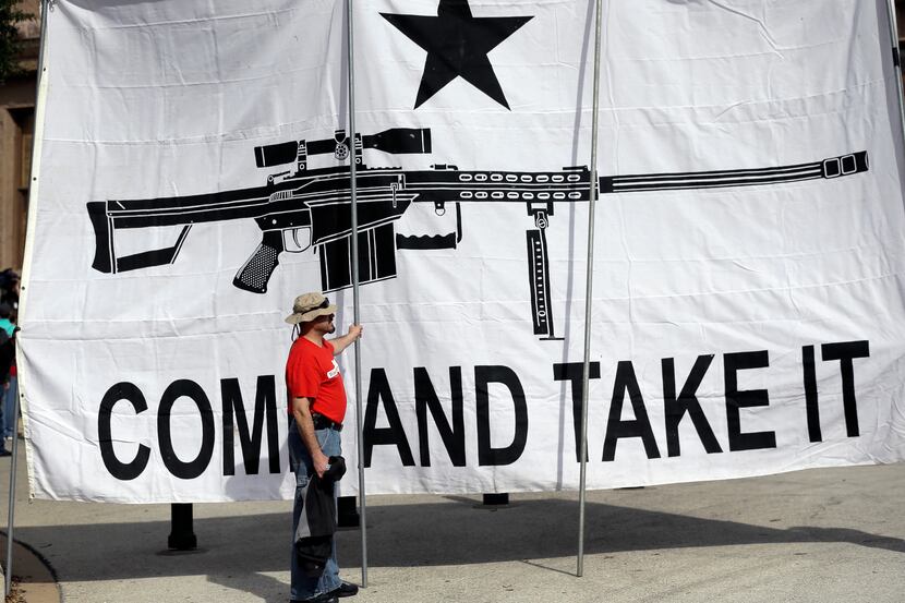 A demonstrator helps hold a large "Come and Take It" banner at a rally in support of open...