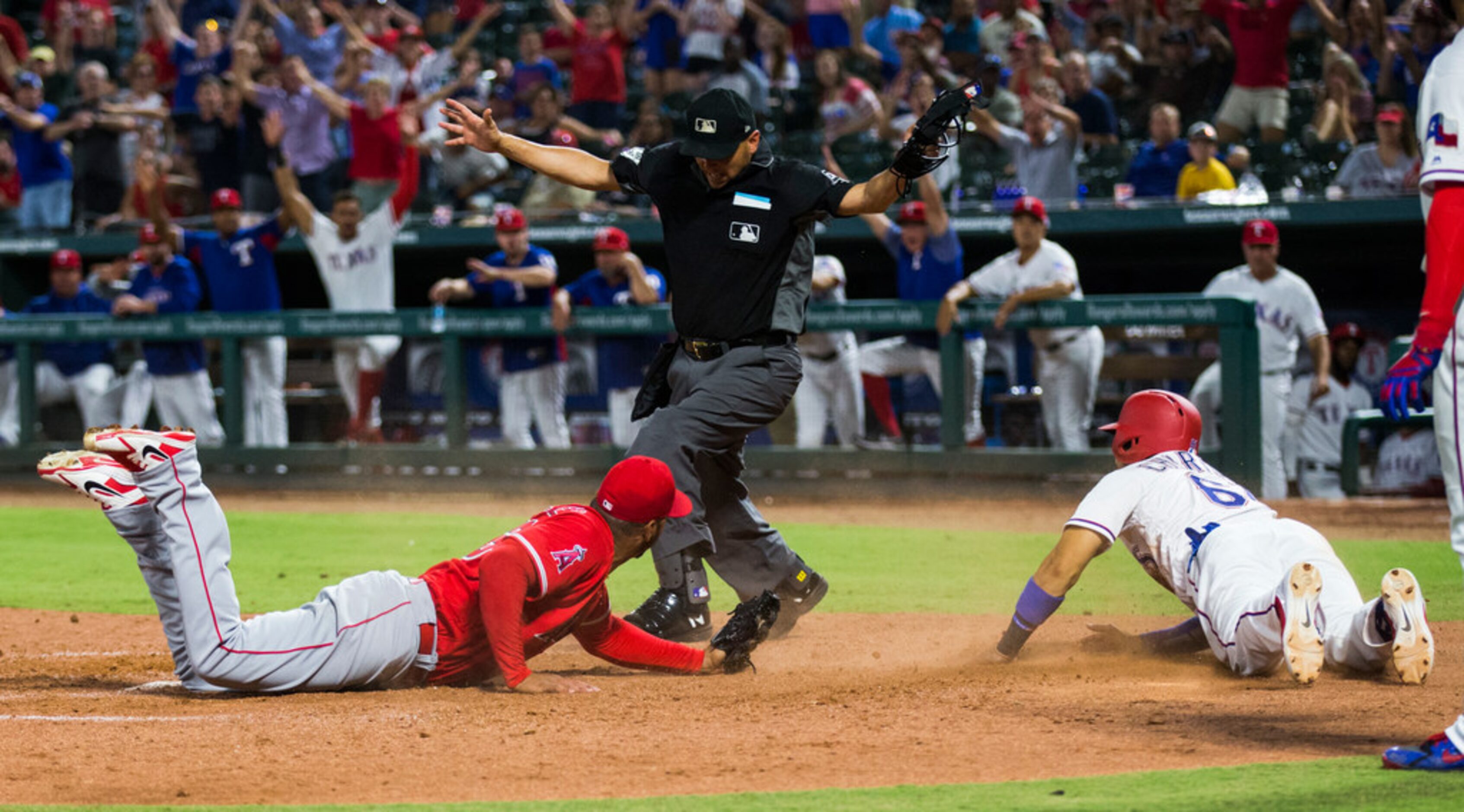 Texas Rangers catcher Robinson Chirinos (61) is called safe after sliding across home plate...