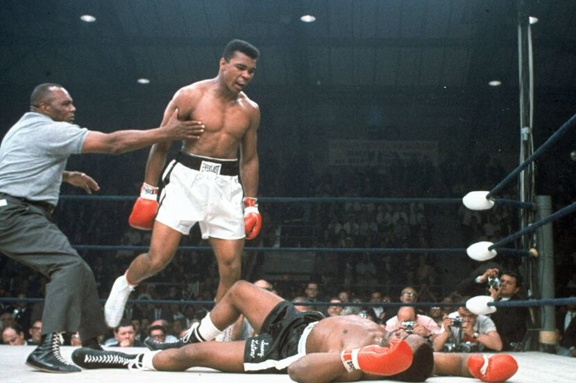  In this May 25, 1965, file photo, heavyweight champion Muhammad Ali is held back by referee...