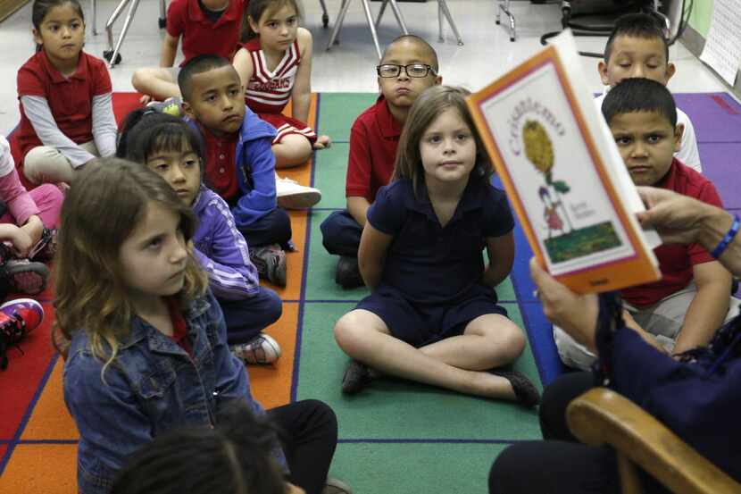 First grade students in Cruz Vargas' dual language class listen to her read a book in...
