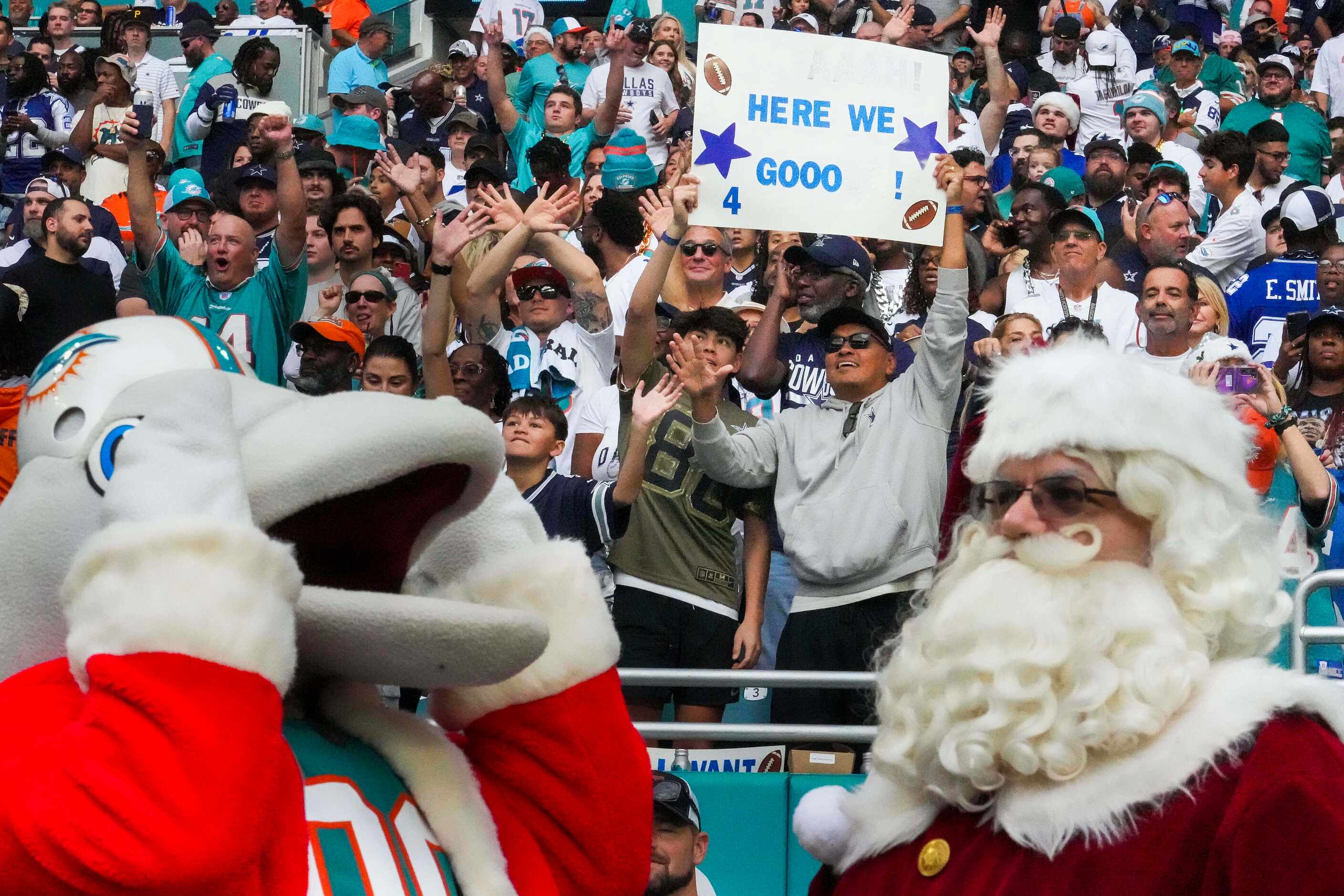 Dallas Cowboys fans cheer behind the Miami Dolphins mascot and Santa Claus before an NFL...