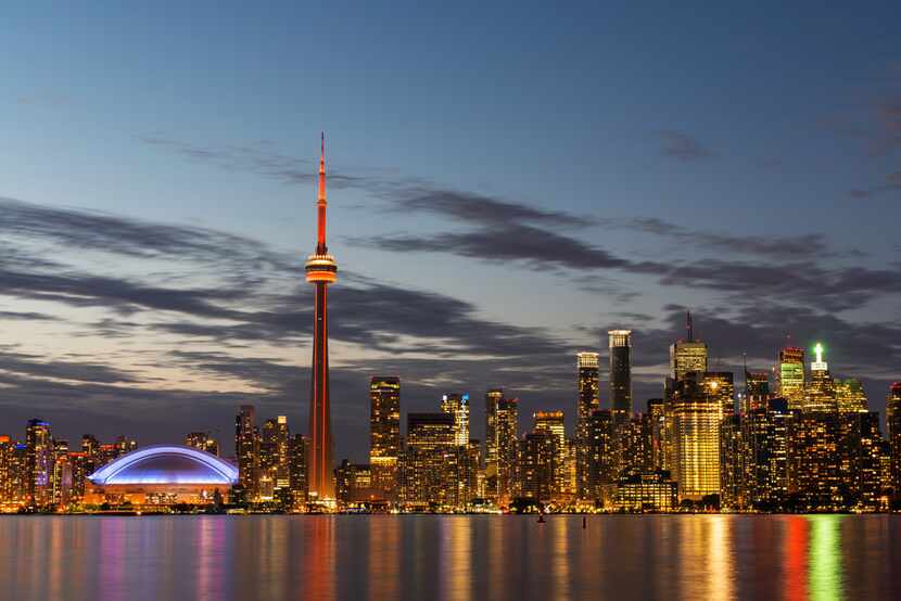 The illuminated Toronto skyline with Lake Ontario in the foreground.