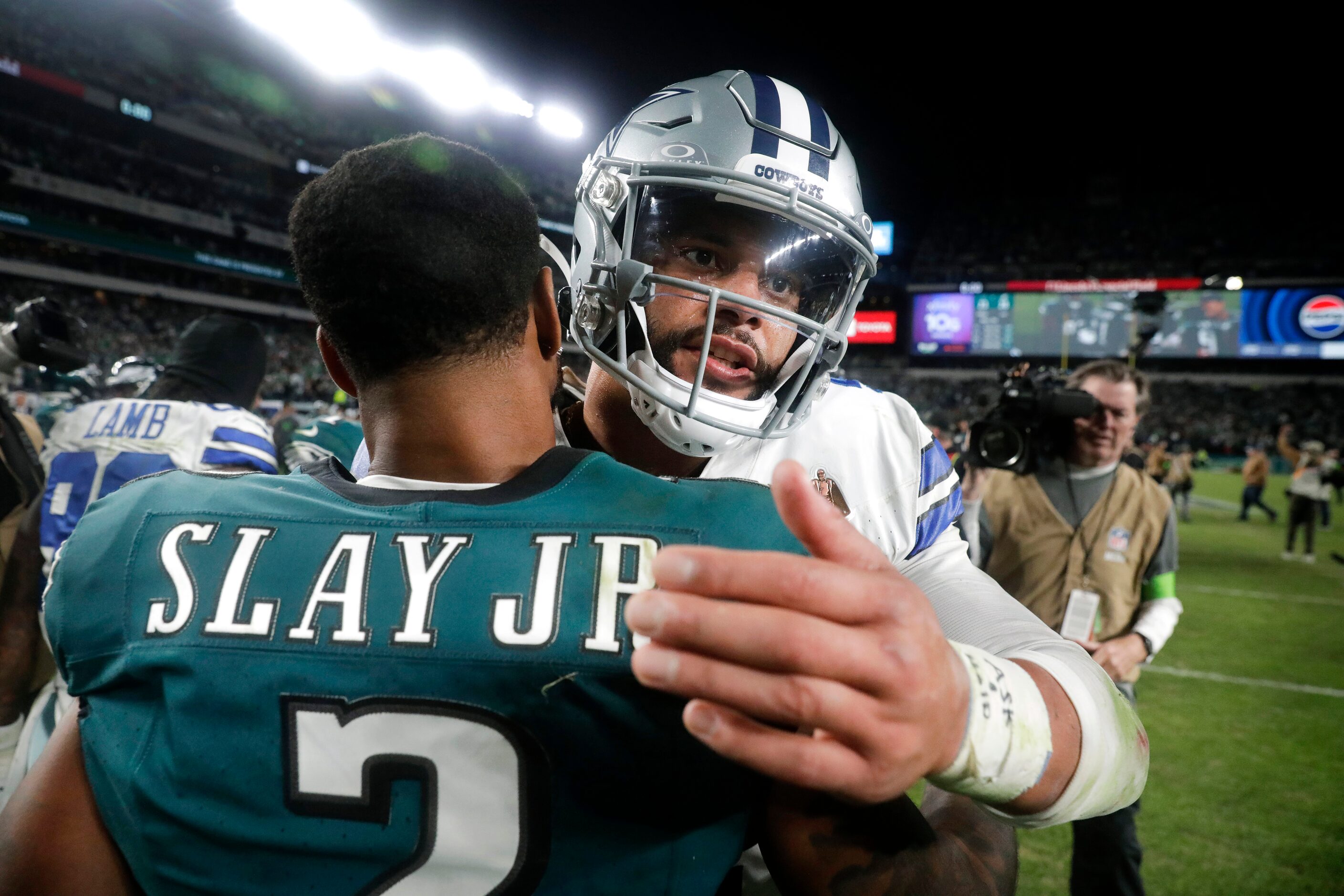 Dallas Cowboys quarterback Dak Prescott (4) receives a hug from Philadelphia Eagles...