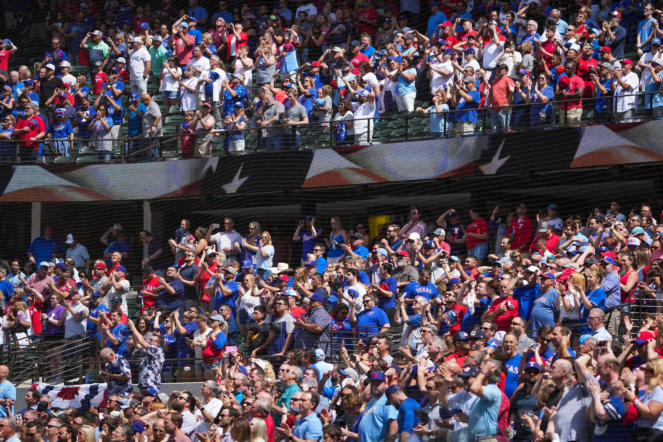 Fans stand for the national anthem before the Texas Rangers home opener against the Colorado...