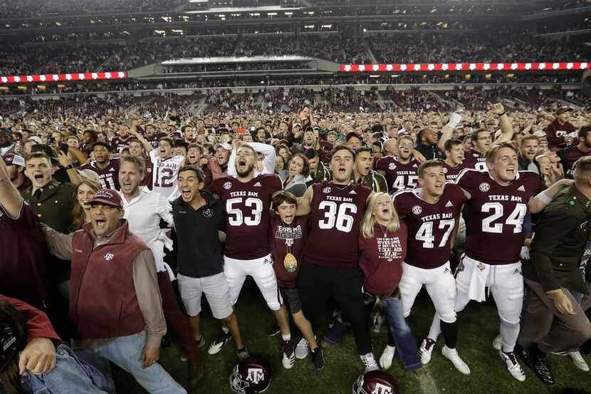 Fans and students join Texas A&M football players on the field after an NCAA college...