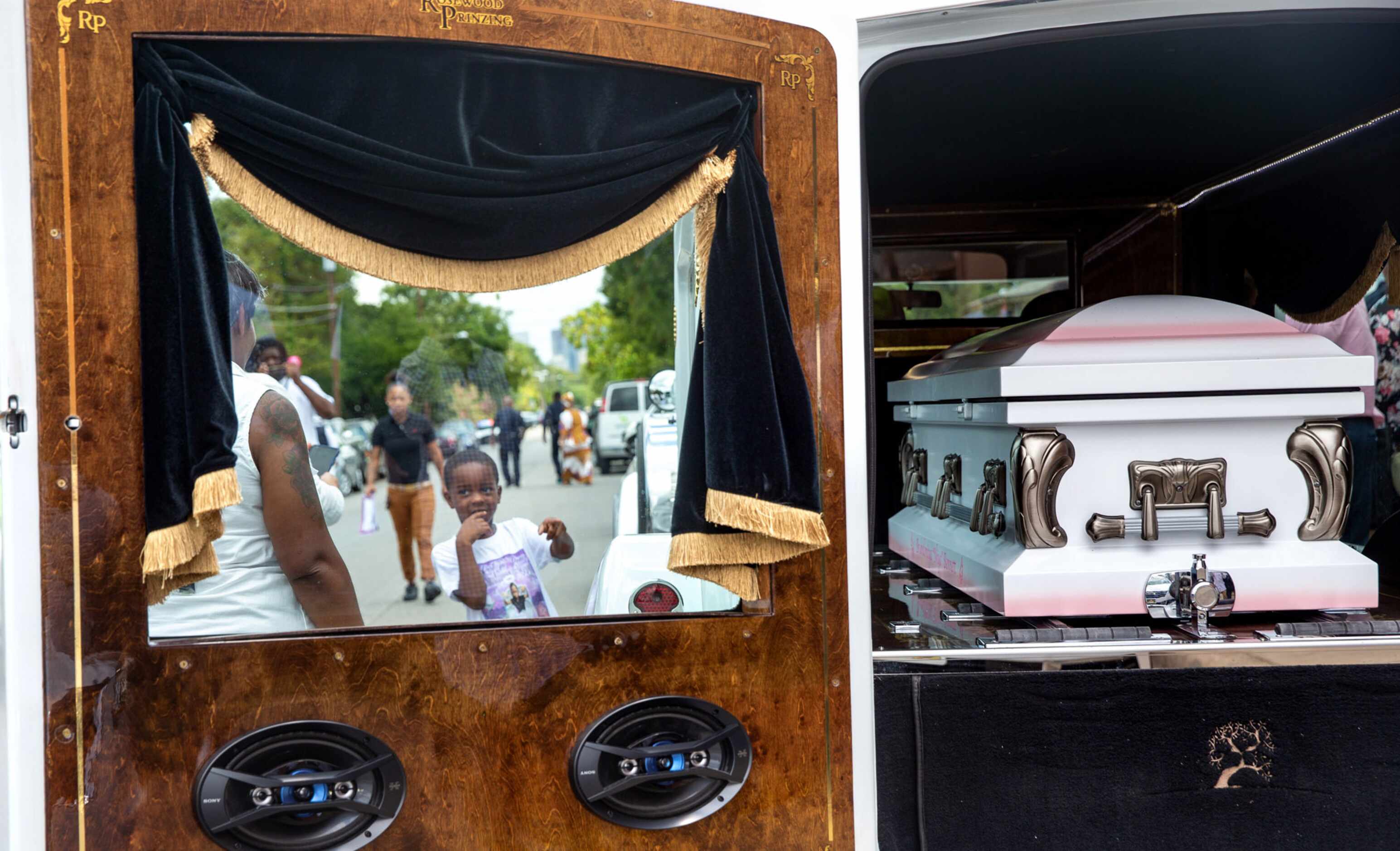 A boy points near the hearse with the casket holding the body of 9-year-old shooting victim,...