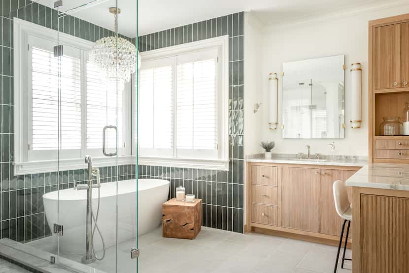 Primary bathroom with large, glass-enclosed shower, freestanding bathtub, stool next to...