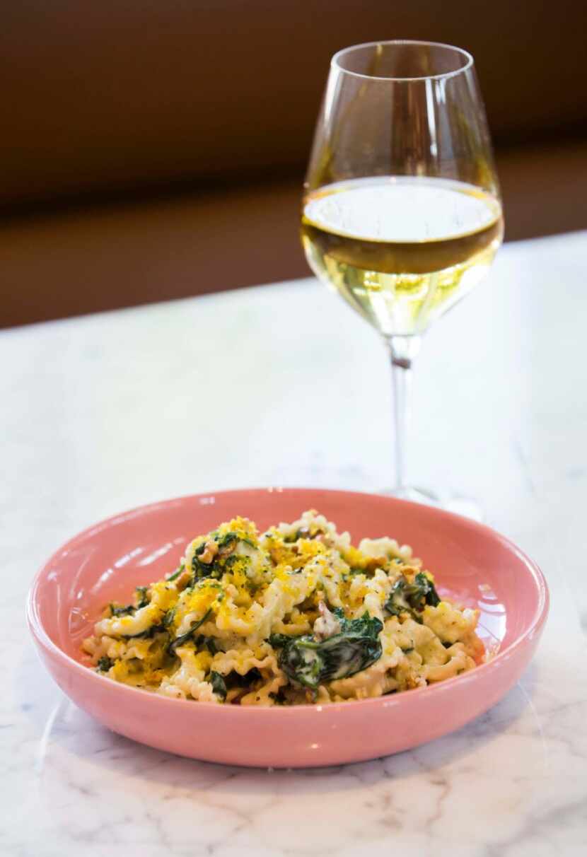 Mafaldine carbonara with guanciale, spinach, walnuts and lemon and a glass of white wine at...