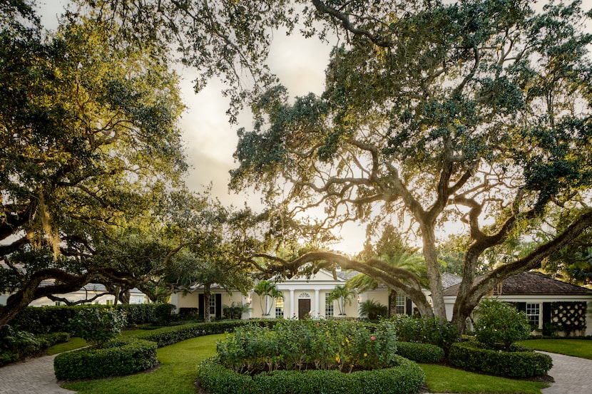 Exterior of Georgian-style home surrounded by mature trees, hedges